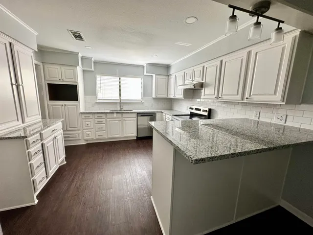 a kitchen with granite countertop cabinets stainless steel appliances a sink and a window