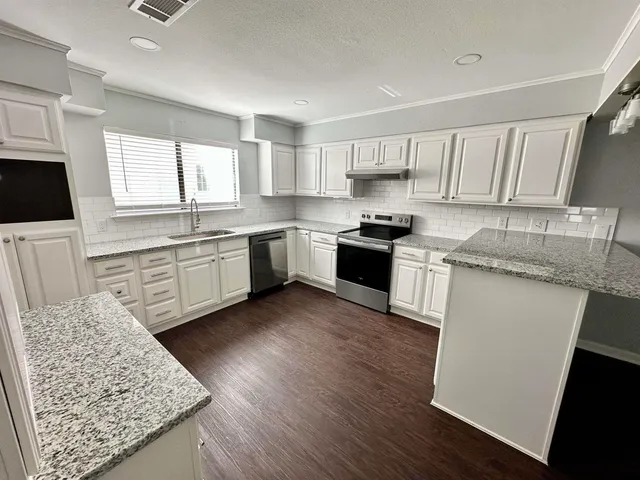 a kitchen with stainless steel appliances granite countertop wooden cabinets a sink a stove a refrigerator and island