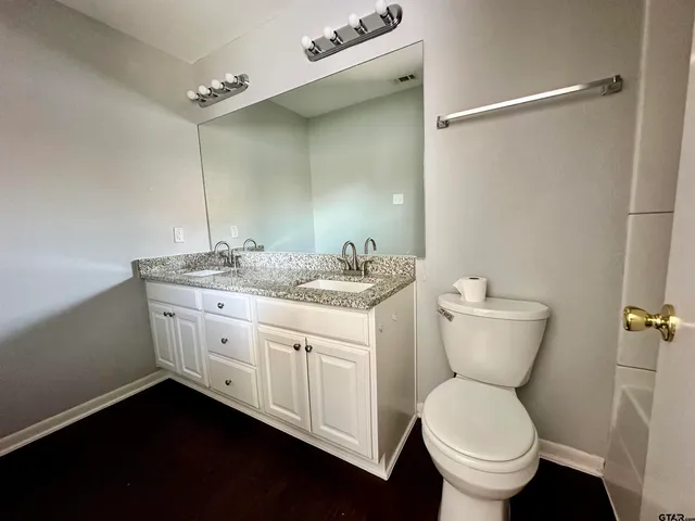 a bathroom with a granite countertop toilet a sink and a mirror