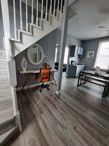 a living room with stainless steel appliances furniture wooden floor and a window