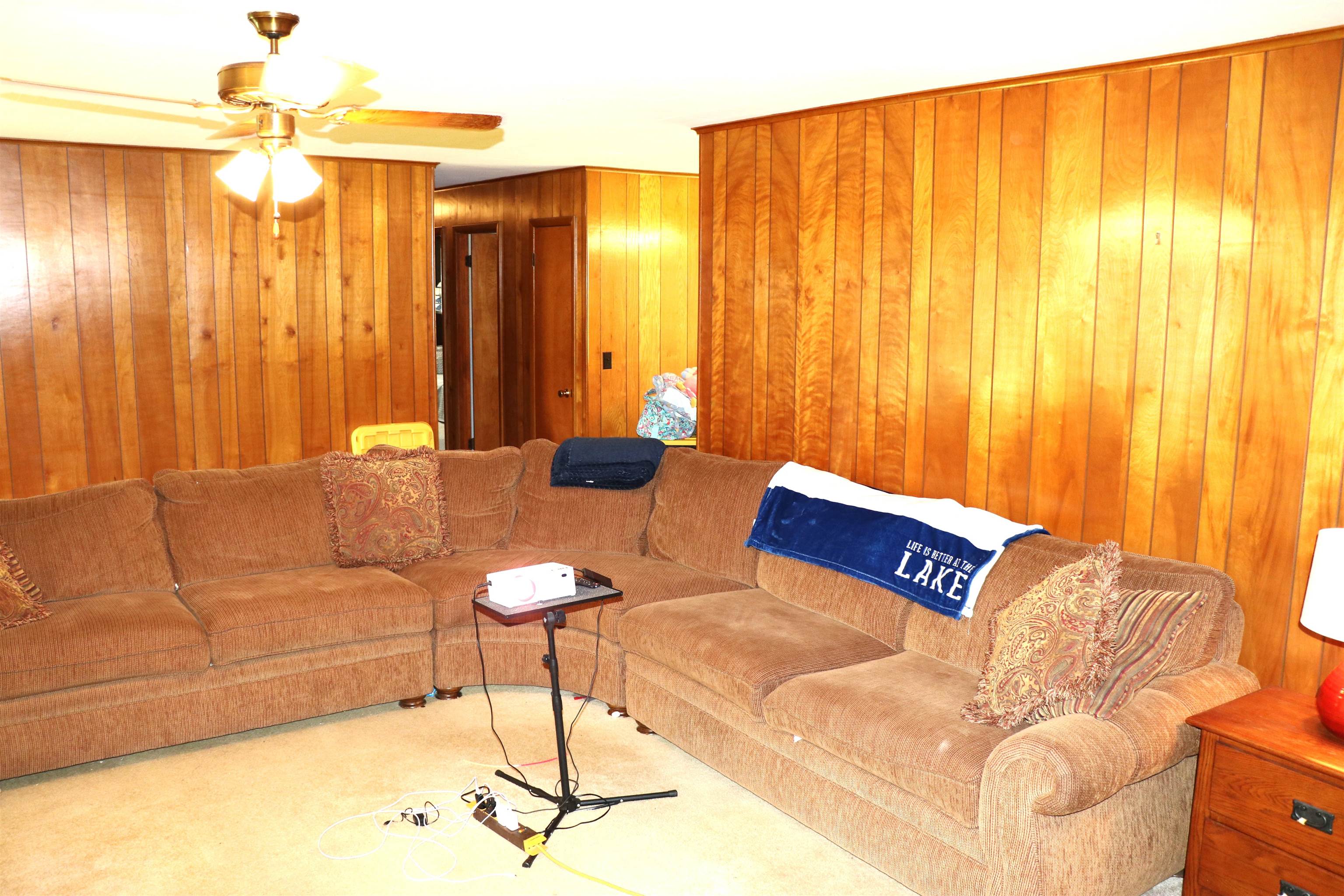 160 Patrick Drive Springville, TN 38256 - Photo 3 of 34 Living area featuring wood paneling throughout, a ceiling fan with light fixture, and carpeted flooring