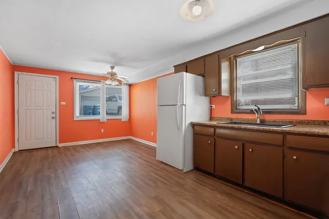 a kitchen with stainless steel appliances granite countertop a refrigerator a sink dishwasher a stove and a large countertops with wooden floor