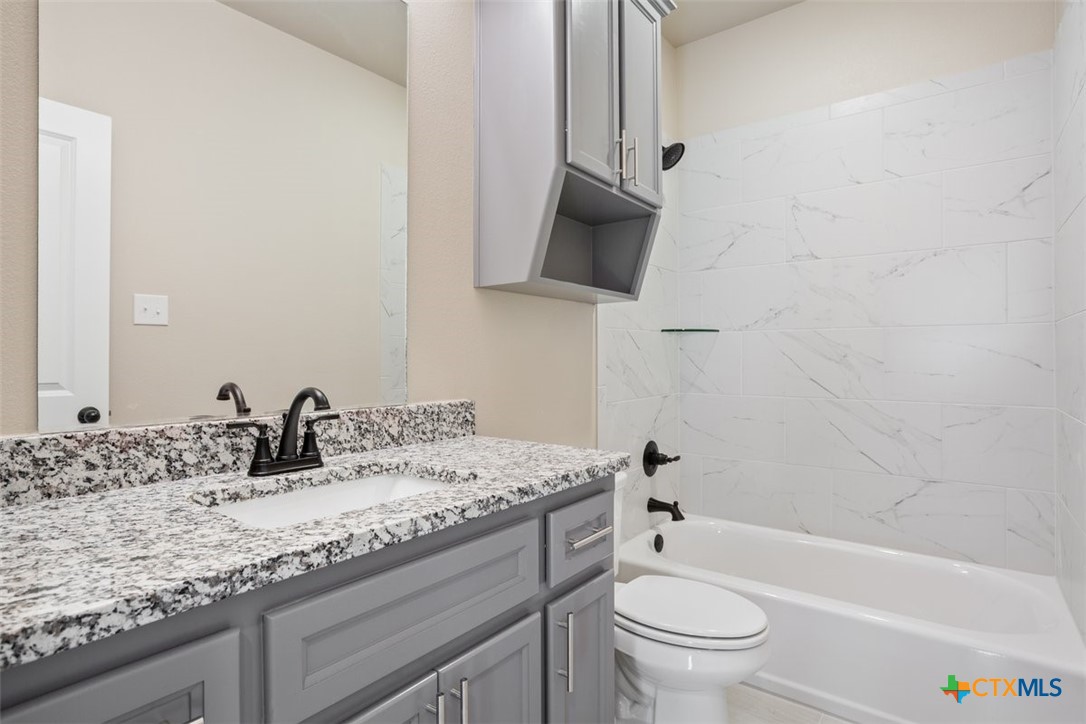 3824 Keller Road Temple, TX 76504 - Photo 22 of 28 a bathroom with a granite countertop sink a toilet and a bathtub
