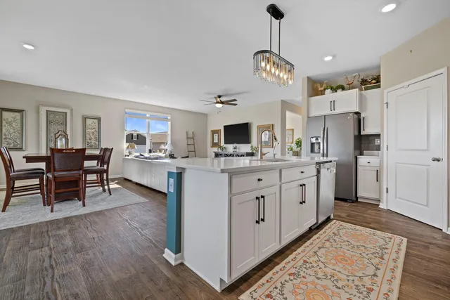 a kitchen with stainless steel appliances kitchen island granite countertop a refrigerator a stove and white cabinets with wooden floor