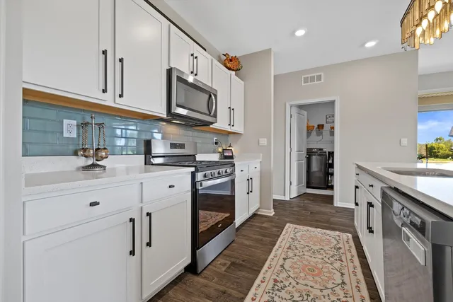 a kitchen with cabinets stainless steel appliances and wooden floor