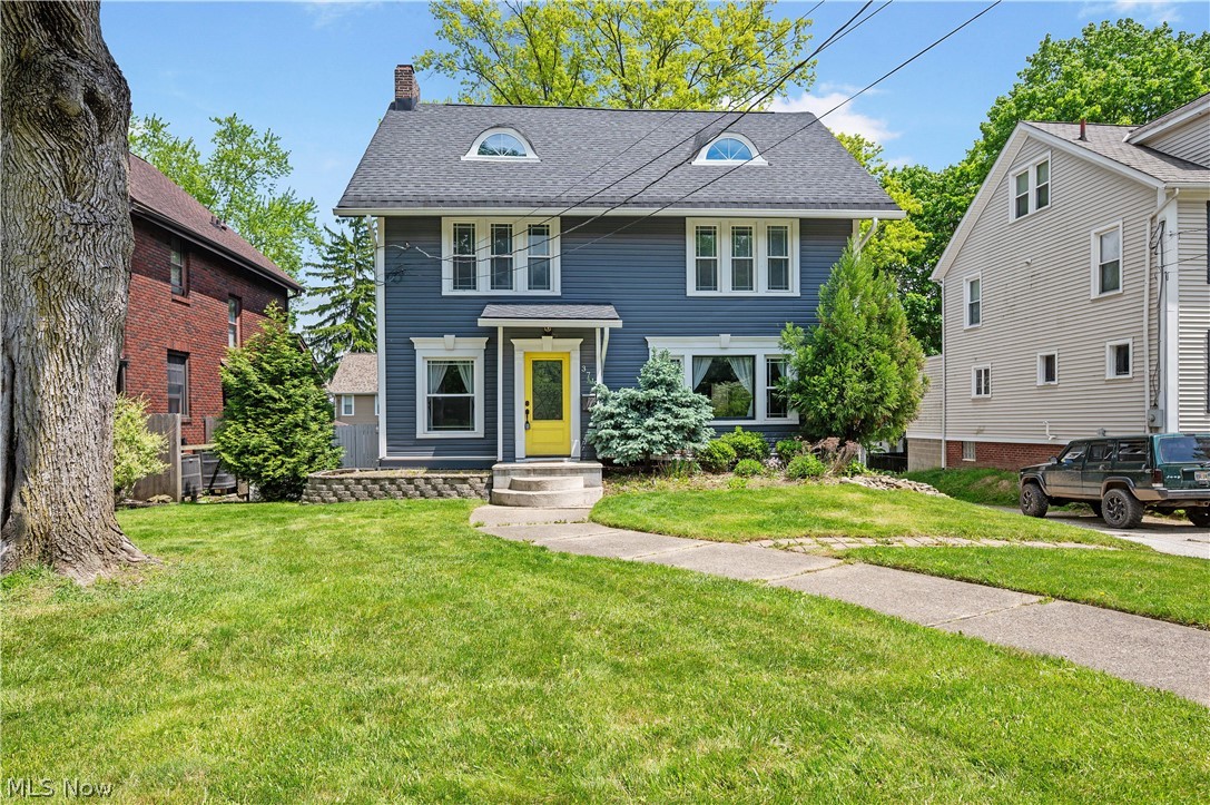 371 Merriman Road Akron, OH 44303 - Photo 1 of 27 Two-story residence featuring a dark blue facade with white trim, a striking yellow front door, and a gray shingle roof