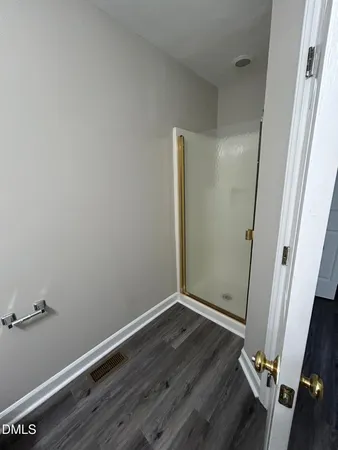 an empty room with wooden floor and mirror