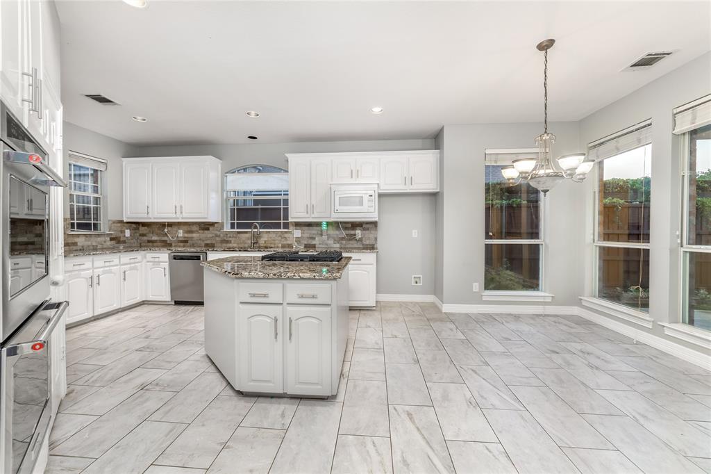 5801 Yeary Road Plano, TX 75093 - Photo 10 of 33 Kitchen featuring white cabinetry, a central island with a cooktop, stone countertops, and a tile backsplash
