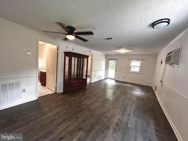 a view of an empty room with window and wooden floor