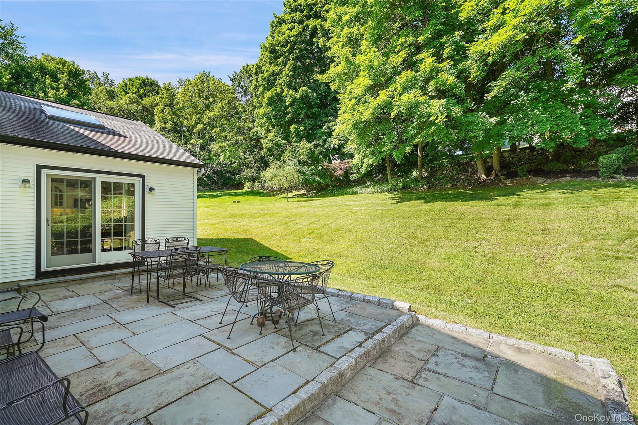 623 Cardinal Road Cortlandt Manor, NY 10567 - Photo 34 of 40 a view of a patio with lawn chairs under an umbrella next to a yard