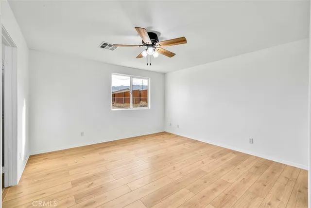an empty room with a window and ceiling fan