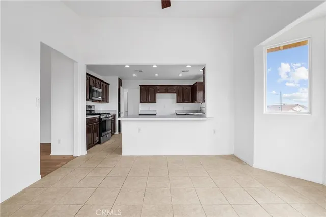 a large white kitchen with a sink and dishwasher a stove top oven with chairs