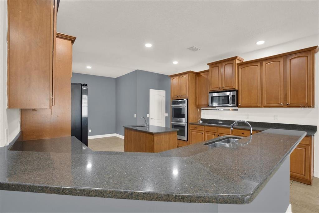 13397 Hunters Point Street Spring Hill, FL 34609 - Photo 11 of 38 a kitchen with stainless steel appliances granite countertop a sink a stove and a refrigerator