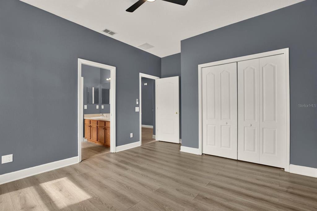 13397 Hunters Point Street Spring Hill, FL 34609 - Photo 22 of 38 a view of an empty room with wooden floor and a bathroom