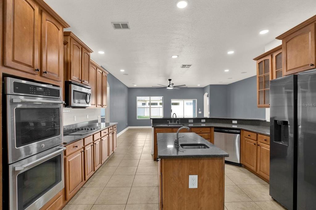 13397 Hunters Point Street Spring Hill, FL 34609 - Photo 7 of 38 a kitchen with stainless steel appliances granite countertop a stove a sink and a refrigerator