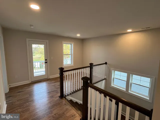 a view of a hallway with wooden floor and staircase