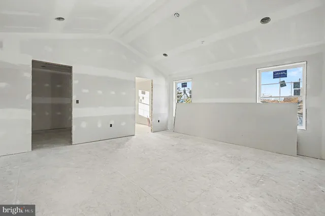 an empty room with windows and refrigerator