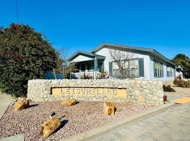 a view of a house with large windows and flower plants with wooden fence
