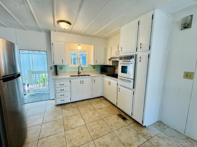 a kitchen with stainless steel appliances a sink a stove a refrigerator cabinets and a window