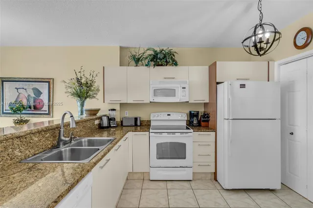 a white kitchen with stainless steel appliances a white refrigerator stove a sink and dishwasher