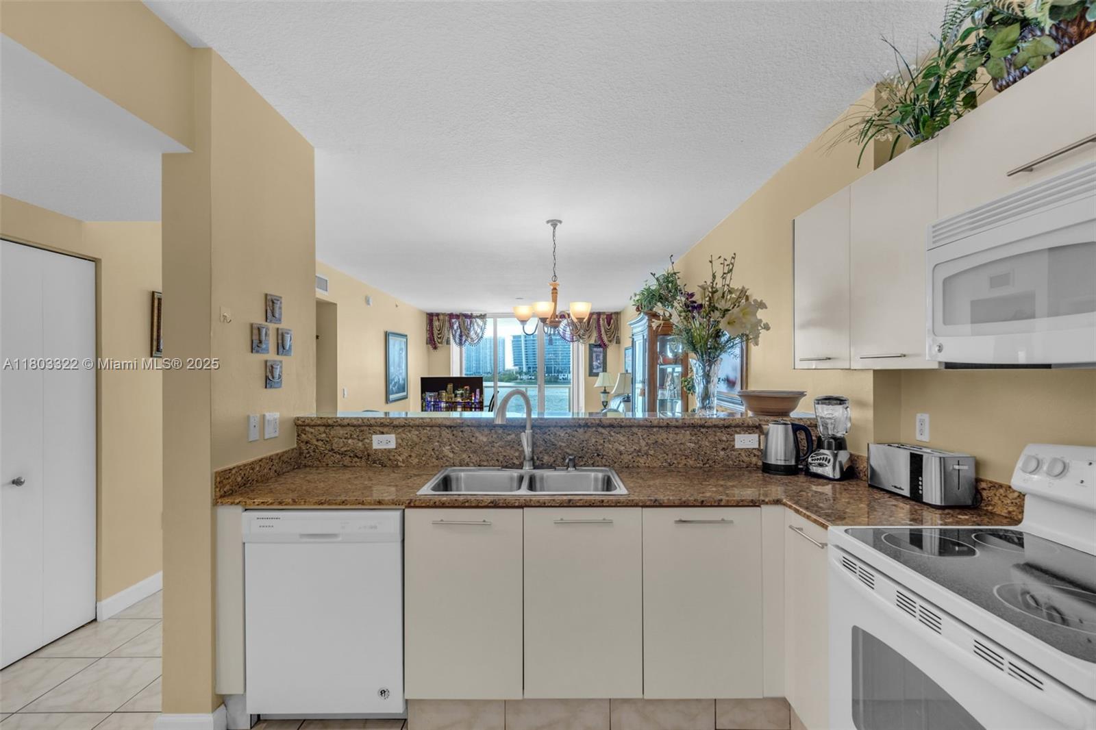 18100 North Bay Road, Unit 404 Sunny Isles Beach, FL 33160 - Photo 10 of 34 a kitchen with granite countertop a sink a stove and cabinets
