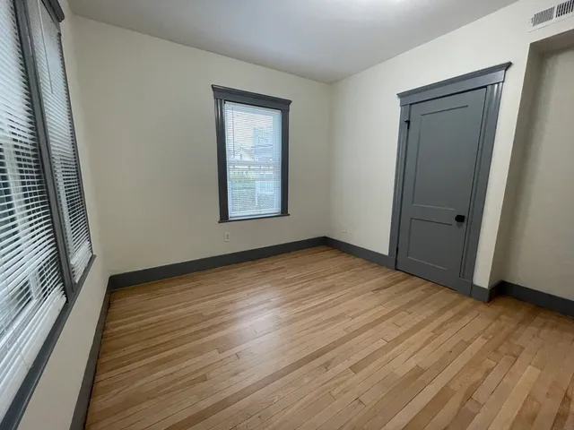 an empty room with wooden floor and windows