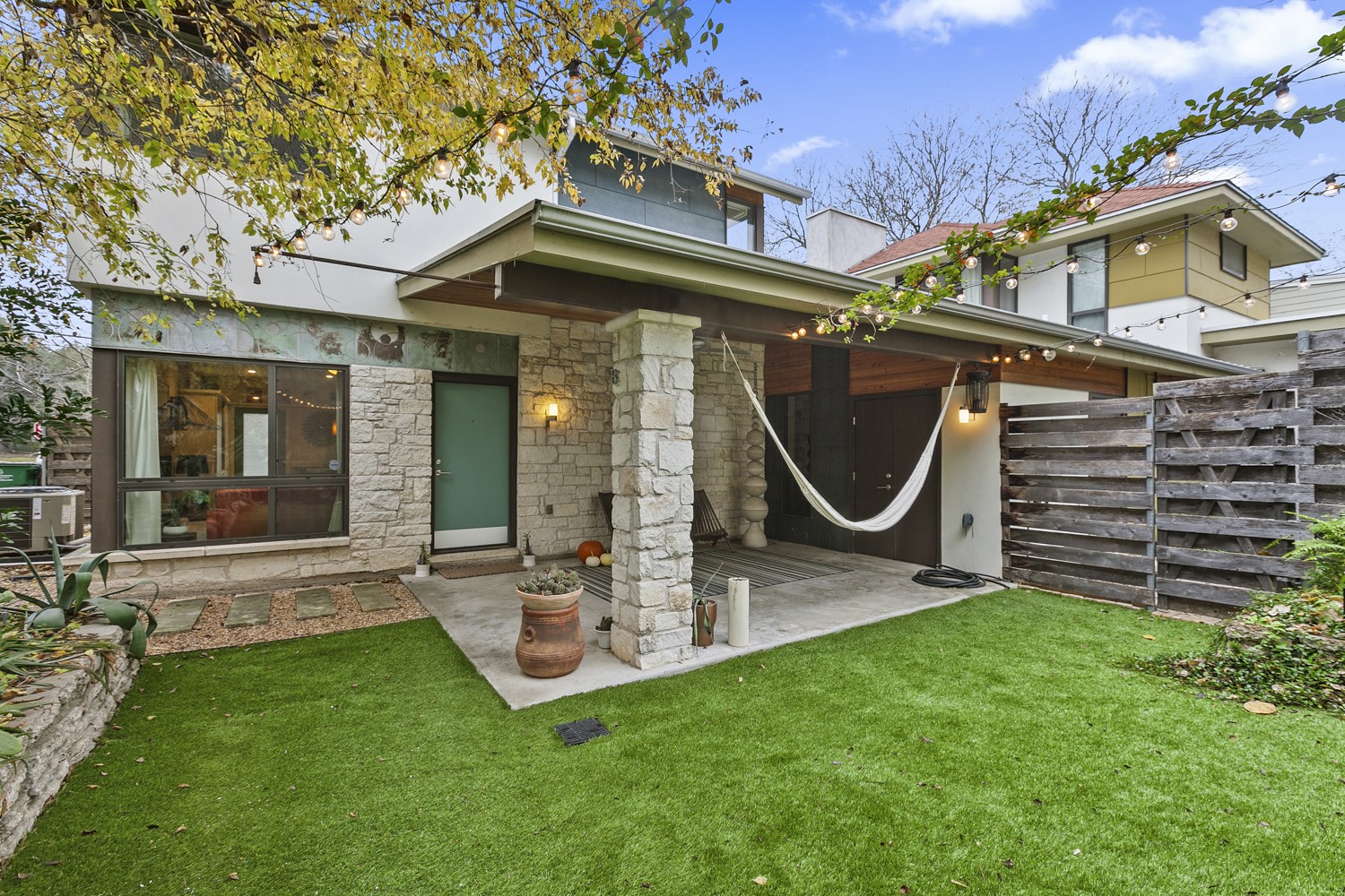 805 Cumberland Road, Unit B Austin, TX 78704 - Photo 2 of 37 This is a great view of the courtyard and patio for this unit. Notice the hanging lights and natural landscaping. The grass is Astroturf so enjoy lush green view all year round.