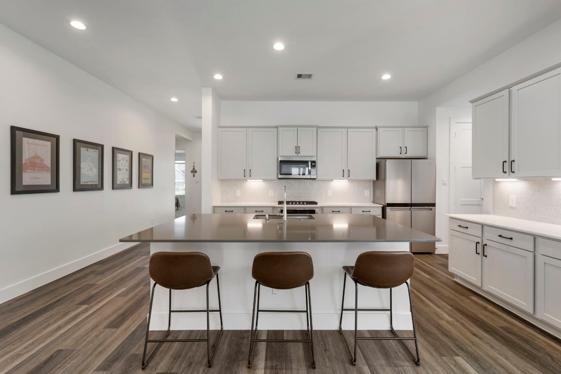 13757 Rising Sun Lane Conroe, TX 77384 - Photo 8 of 39 a kitchen with stainless steel appliances granite countertop a stove a sink a refrigerator white cabinets and chairs with wooden floor