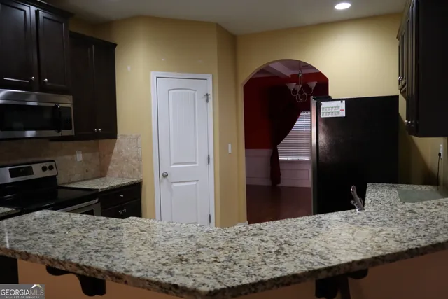 a living room with stainless steel appliances kitchen island granite countertop a stove refrigerator and microwave