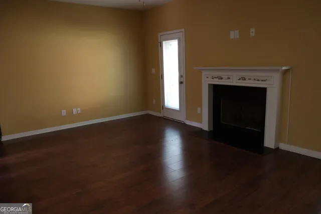 a view of empty room with wooden floor and fireplace