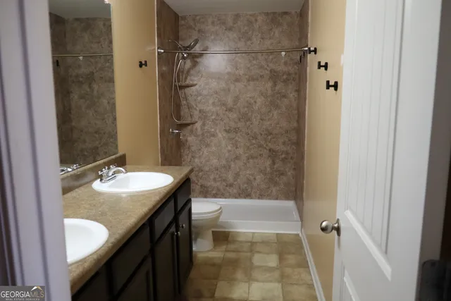 a bathroom with a granite countertop shower sink and mirror