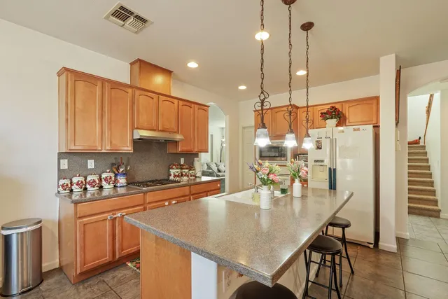a large living room with stainless steel appliances kitchen island granite countertop a sink and a couch