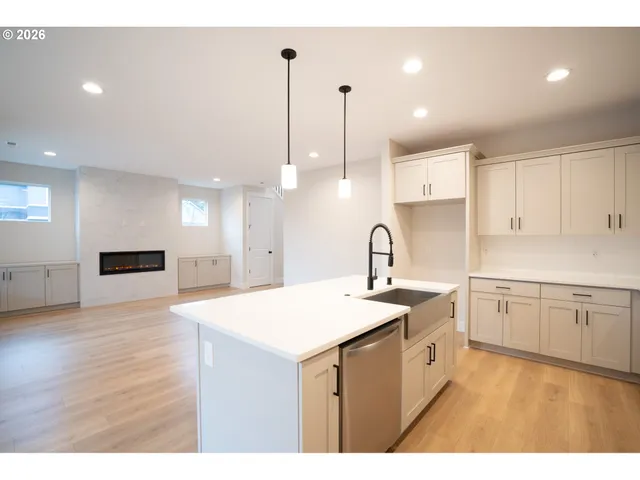 a kitchen with a sink a stove a refrigerator and white cabinets with wooden floor