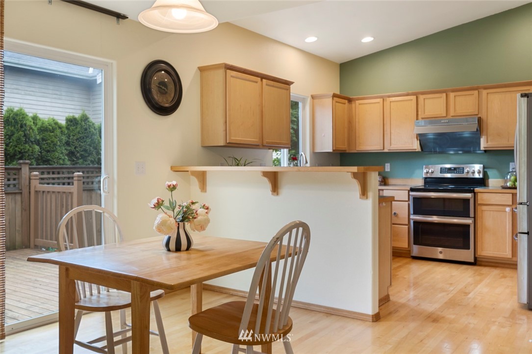 3530 186th Place Southeast Bothell, WA 98012 - Photo 7 of 38 a kitchen with a table chairs a stove a microwave and cabinets