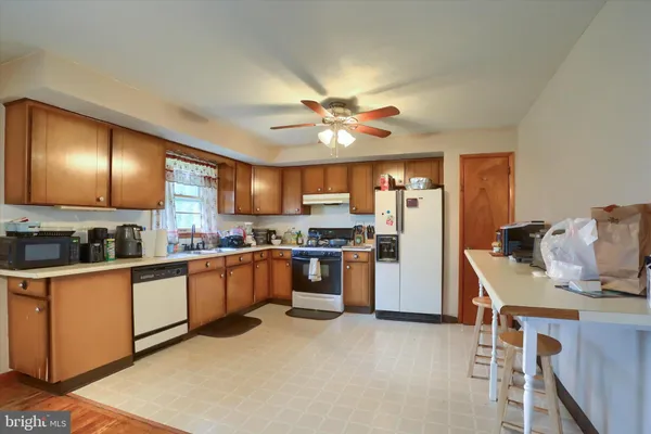 a kitchen with stainless steel appliances granite countertop a refrigerator a sink dishwasher a stove with wooden cabinets and floor