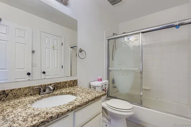a bathroom with a granite countertop sink a toilet and a shower