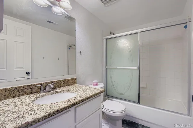 a bathroom with a granite countertop sink toilet and shower