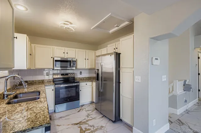 a kitchen with stainless steel appliances granite countertop a refrigerator stove and sink