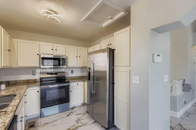 a kitchen with stainless steel appliances granite countertop a refrigerator stove and sink
