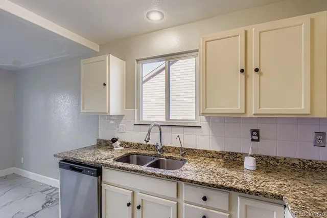 a kitchen with granite countertop a sink stove and cabinets