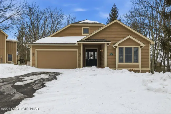a front view of a house with a yard covered in snow