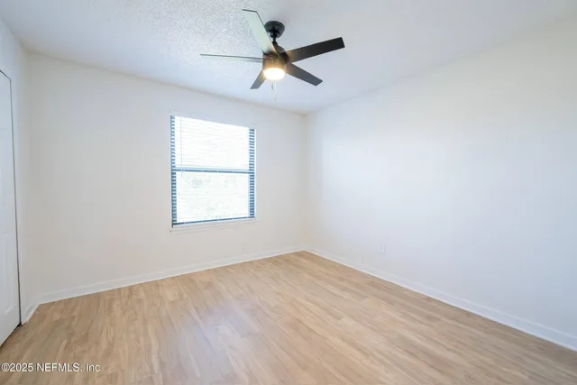 an empty room with ceiling fan and windows