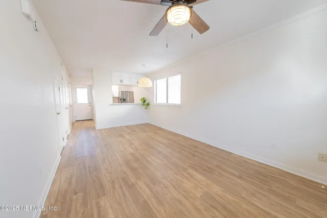 an empty room with wooden floor fan and windows