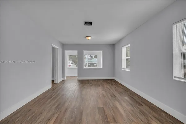 an empty room with wooden floor and windows