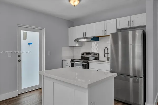 a kitchen with stainless steel appliances a refrigerator a stove a sink and white cabinets