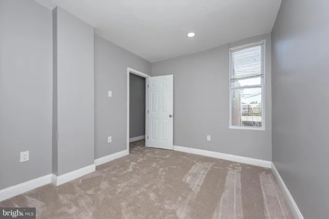 a view of an empty room with window and closet area