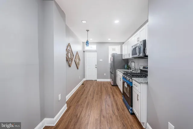 a walk in closet with wooden floor