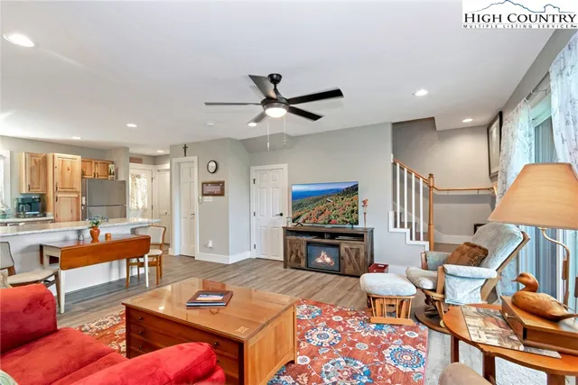 a living room with furniture a flat screen tv and kitchen view
