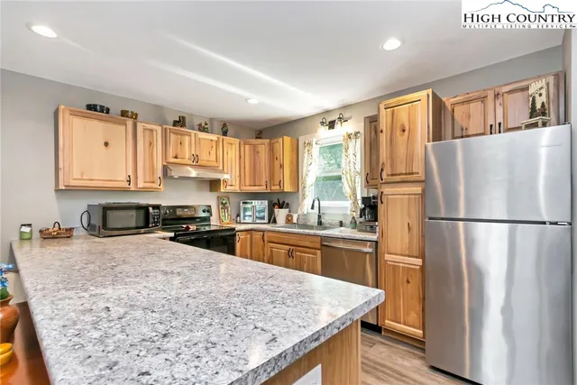 a kitchen with granite countertop a refrigerator stove top oven and sink