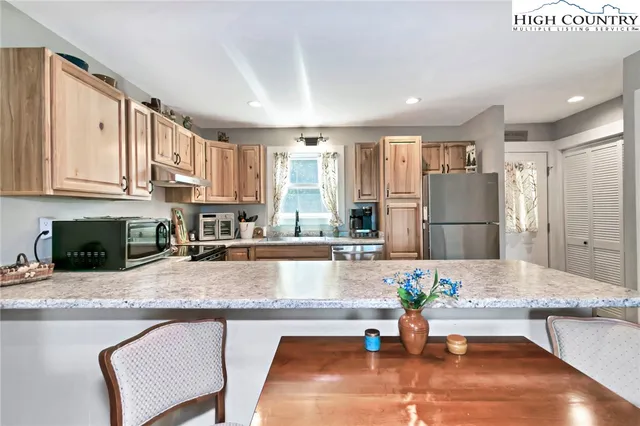 a large kitchen with stainless steel appliances granite countertop a refrigerator a sink a stove and white cabinets